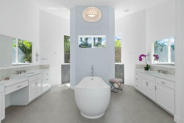 full bath featuring a sink, a freestanding tub, plenty of natural light, and two vanities