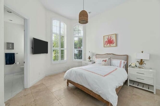 bedroom with ensuite bath, baseboards, and light tile patterned floors