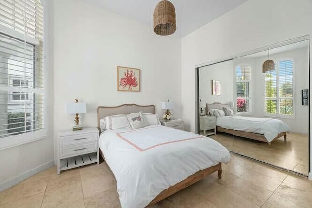 bedroom featuring a closet, light tile patterned flooring, and baseboards