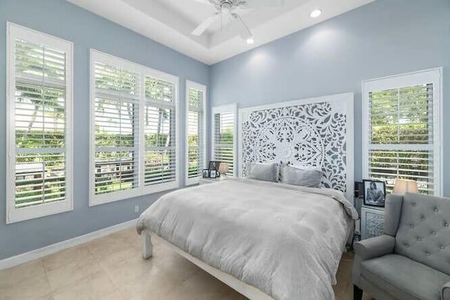 bedroom featuring recessed lighting, a raised ceiling, a ceiling fan, baseboards, and tile patterned floors