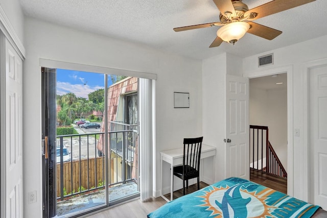 bedroom featuring access to outside, a textured ceiling, visible vents, and wood finished floors