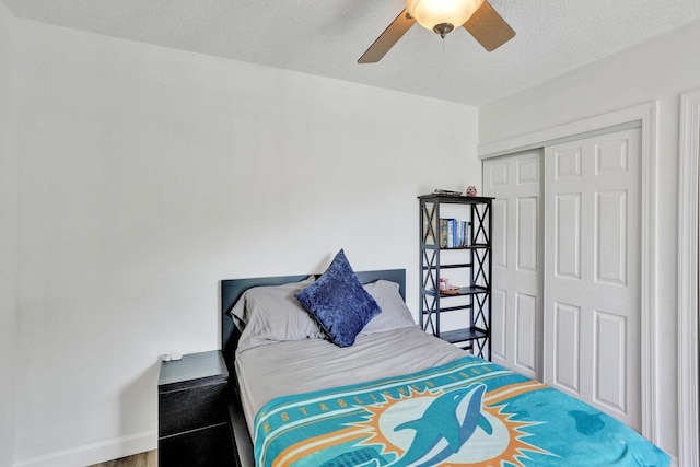 bedroom with a closet, ceiling fan, a textured ceiling, and baseboards