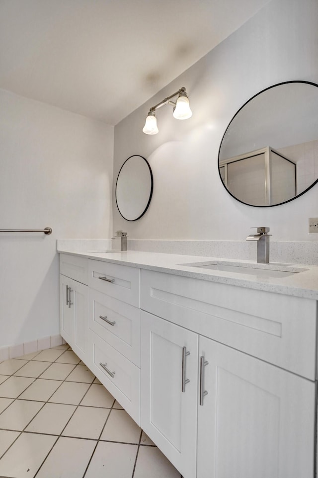 full bath with double vanity, tile patterned flooring, a sink, and baseboards