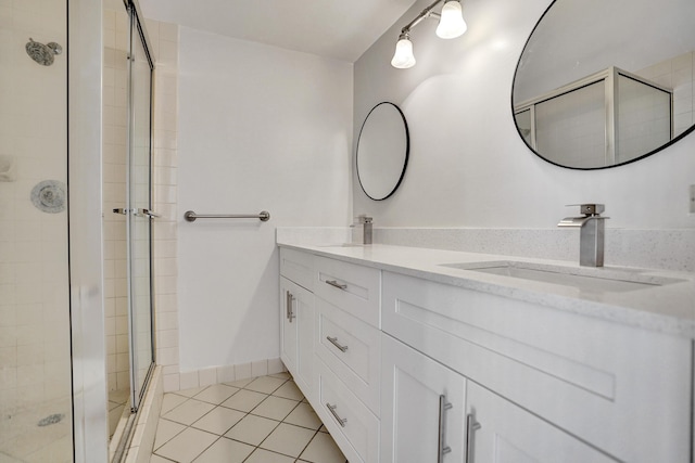 full bathroom featuring double vanity, a stall shower, a sink, baseboards, and tile patterned floors