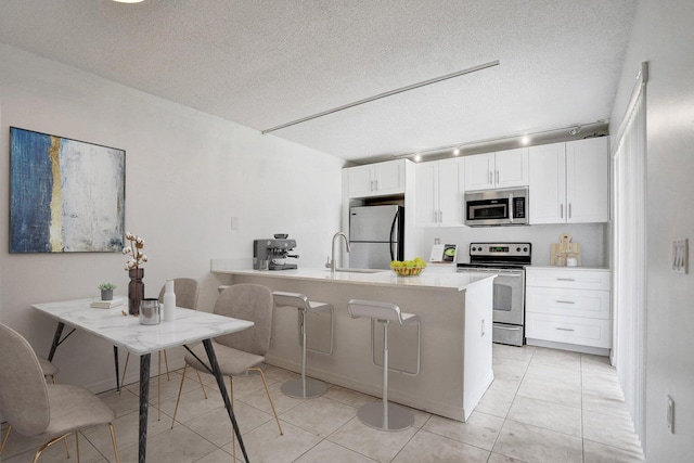 kitchen with light countertops, white cabinets, a peninsula, and appliances with stainless steel finishes