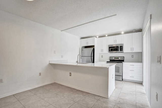 kitchen with stainless steel appliances, light countertops, white cabinets, and a peninsula