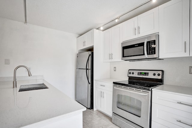 kitchen with light tile patterned flooring, stainless steel appliances, a sink, white cabinets, and light countertops