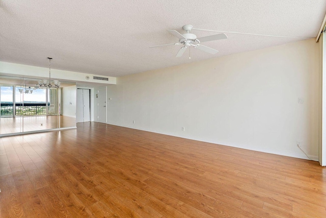 unfurnished room featuring light wood-style flooring, visible vents, a textured ceiling, and ceiling fan with notable chandelier