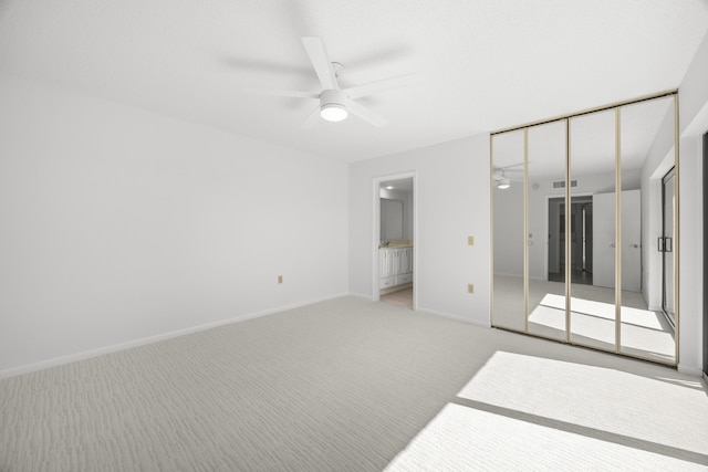 unfurnished bedroom with light carpet, a ceiling fan, visible vents, baseboards, and ensuite bath