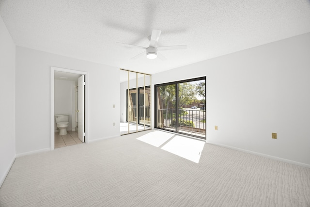 unfurnished bedroom featuring baseboards, ensuite bath, access to outside, a textured ceiling, and carpet flooring