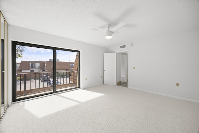 carpeted empty room featuring visible vents, a textured ceiling, and baseboards