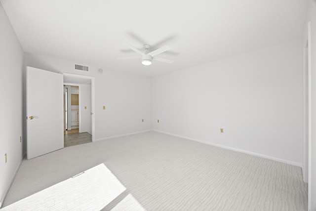 spare room featuring light carpet, ceiling fan, visible vents, and baseboards