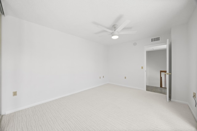 spare room with ceiling fan, baseboards, visible vents, and light colored carpet