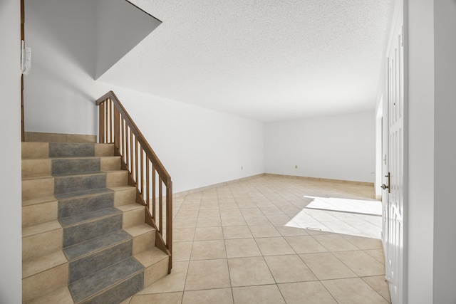 stairway with a textured ceiling and tile patterned floors