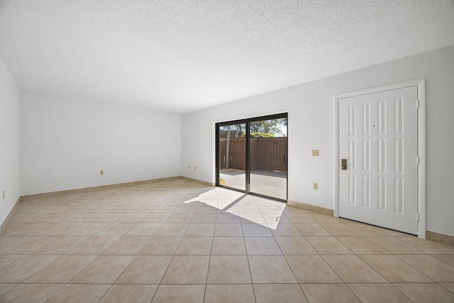 spare room featuring light tile patterned floors, baseboards, and a textured ceiling