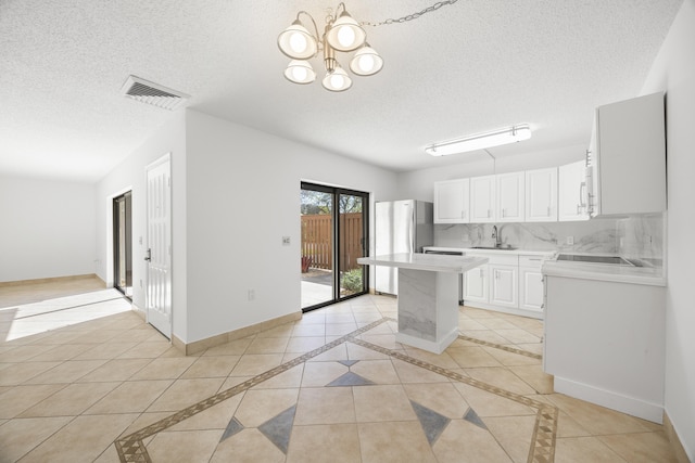 kitchen featuring light countertops, visible vents, backsplash, and baseboards