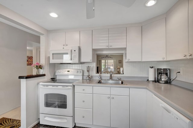 kitchen with white appliances, tasteful backsplash, light countertops, white cabinetry, and a sink