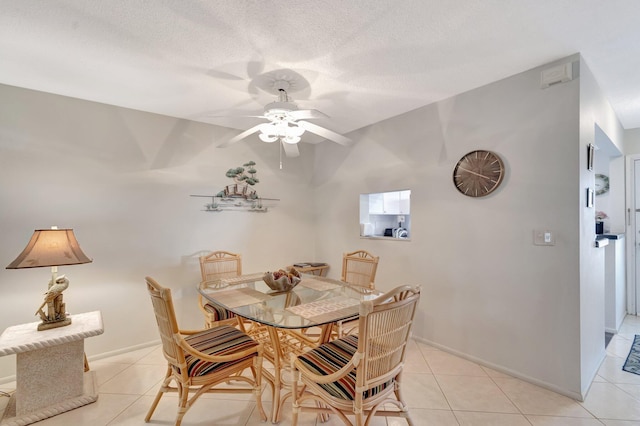 dining space featuring light tile patterned floors, baseboards, and a textured ceiling