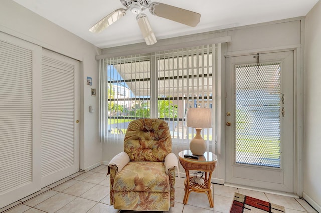 sitting room with light tile patterned floors, plenty of natural light, and a ceiling fan