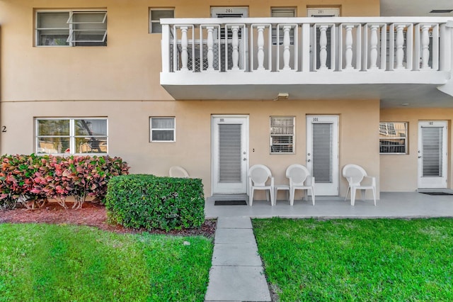 entrance to property featuring a balcony, visible vents, a patio, and stucco siding