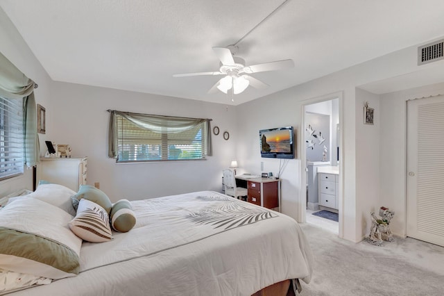 bedroom featuring light carpet, a ceiling fan, visible vents, and connected bathroom