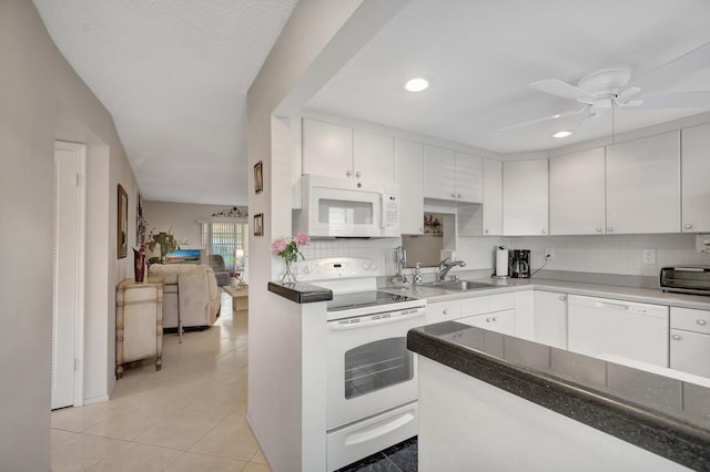 kitchen featuring light tile patterned floors, backsplash, white cabinetry, a sink, and white appliances