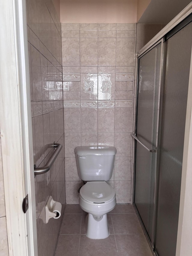 full bath featuring a stall shower, tile walls, toilet, and tile patterned floors