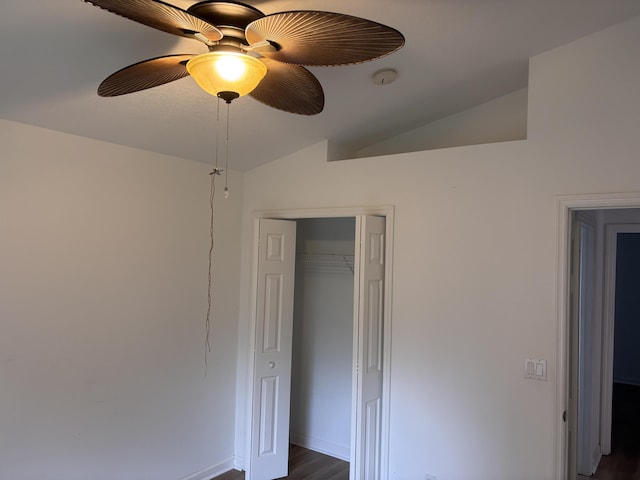 unfurnished bedroom with ceiling fan, baseboards, vaulted ceiling, a closet, and dark wood-style floors