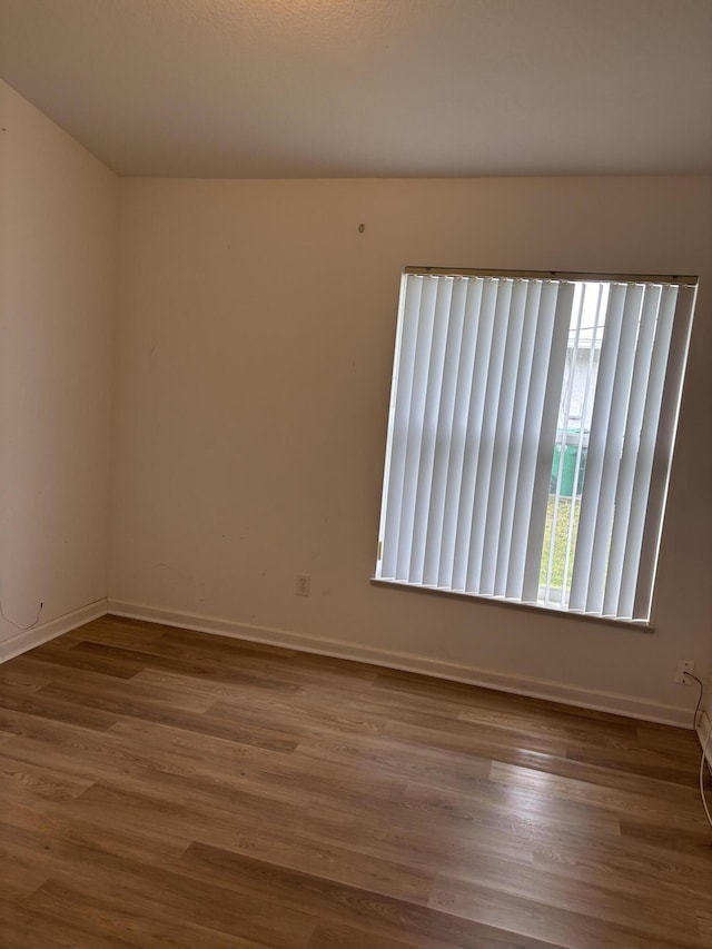 spare room featuring baseboards and wood finished floors