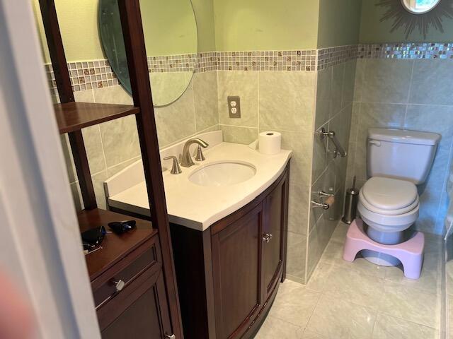 bathroom with tile walls, vanity, toilet, and tile patterned floors