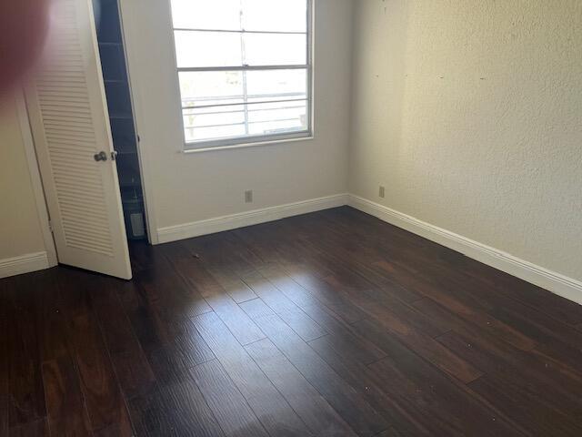 empty room featuring dark wood-style flooring and baseboards