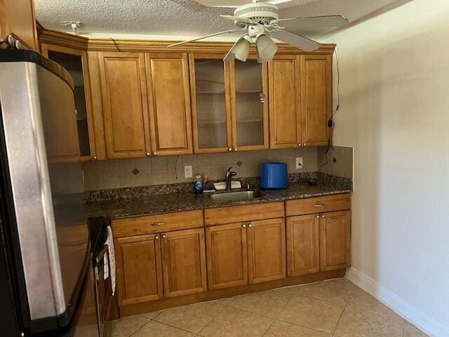 kitchen featuring backsplash, brown cabinetry, and a sink