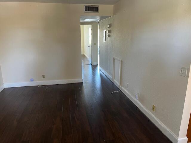 hallway featuring baseboards, visible vents, and dark wood-type flooring