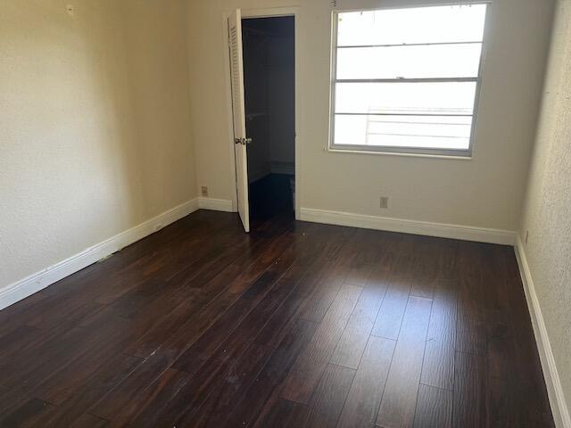 unfurnished room with dark wood finished floors and baseboards