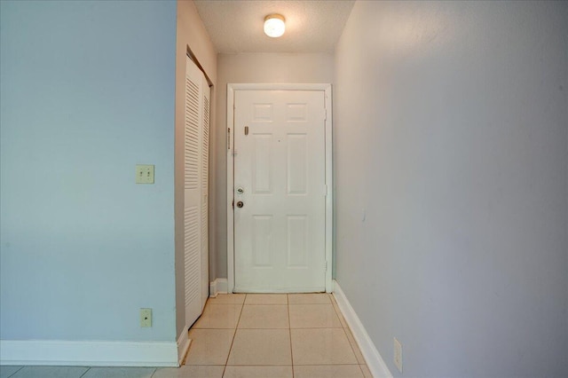 entryway featuring light tile patterned floors, a textured ceiling, and baseboards