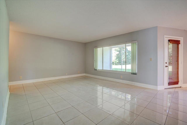 unfurnished room featuring light tile patterned floors, baseboards, and a textured ceiling