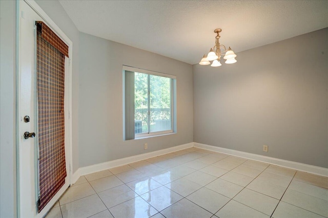 spare room featuring a chandelier, baseboards, and light tile patterned floors