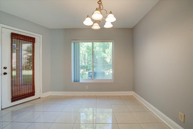 unfurnished room with light tile patterned floors, a notable chandelier, and baseboards