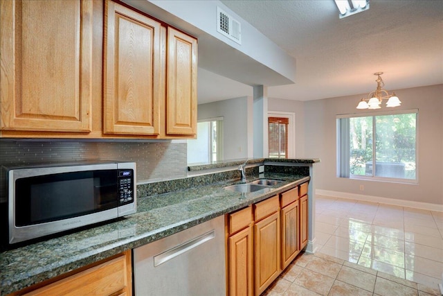 kitchen with stainless steel appliances, a sink, visible vents, dark stone counters, and tasteful backsplash