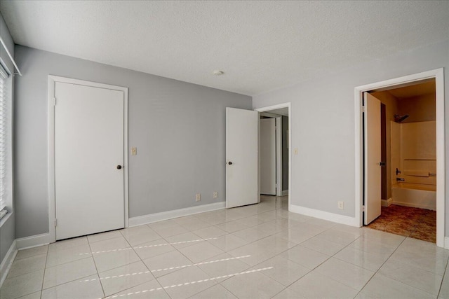 unfurnished bedroom with baseboards, a textured ceiling, and light tile patterned flooring