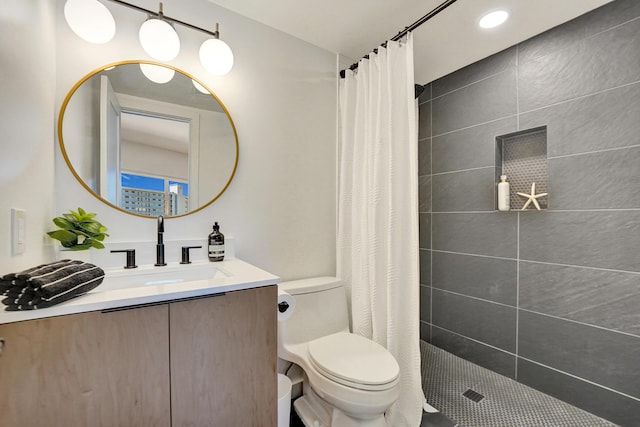 bathroom with tiled shower, vanity, and toilet