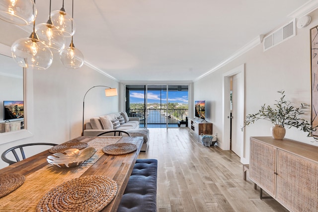 dining space featuring visible vents, ornamental molding, expansive windows, wood finished floors, and a chandelier