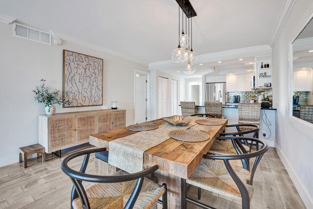 living room featuring baseboards, ornamental molding, visible vents, and light wood-style floors