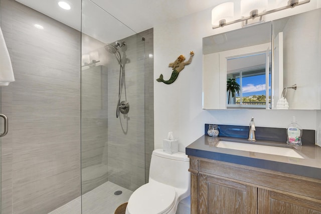 full bathroom featuring toilet, tiled shower, and vanity