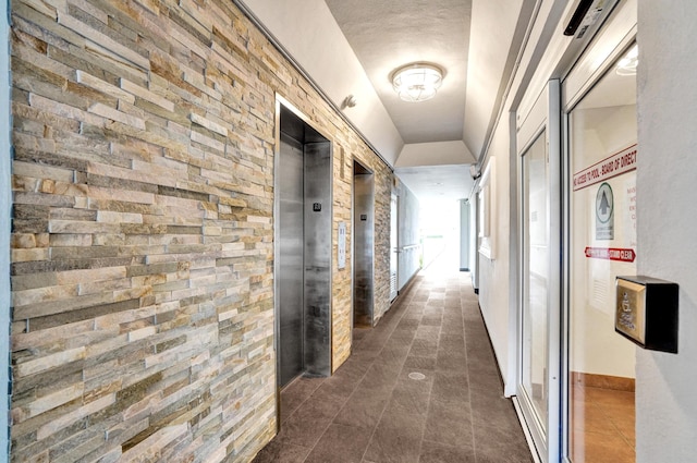 hallway featuring elevator and dark tile patterned floors