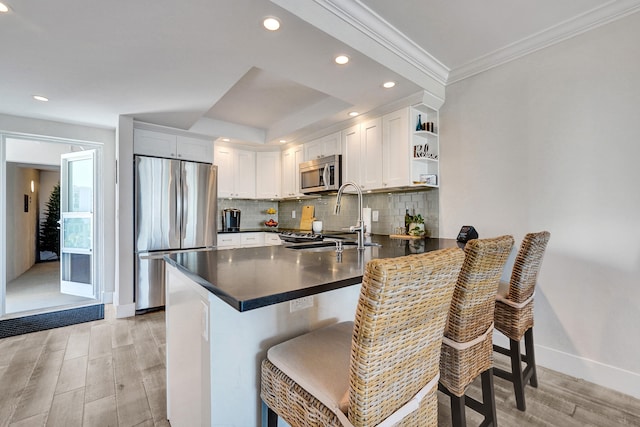 kitchen with appliances with stainless steel finishes, dark countertops, a sink, and a peninsula