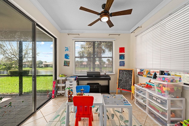 rec room featuring a ceiling fan, a water view, and tile patterned floors