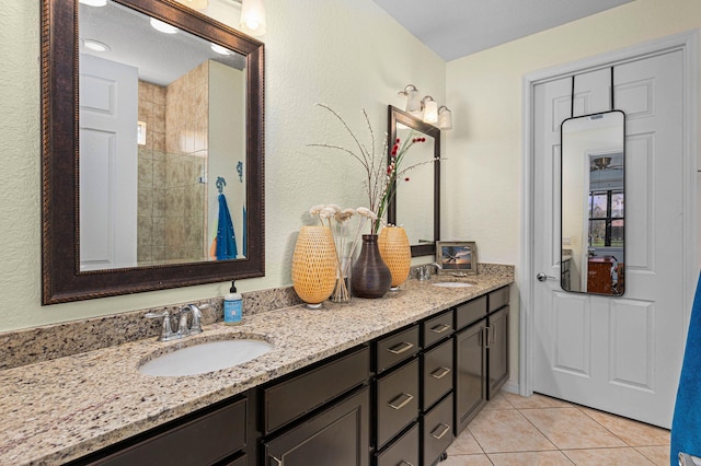 full bathroom with a sink, tile patterned floors, a textured wall, and double vanity