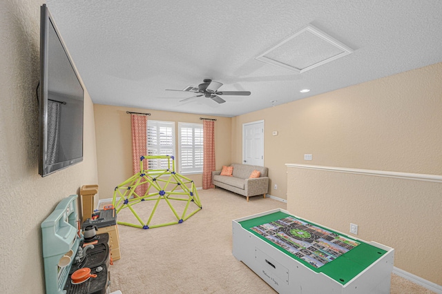 playroom featuring a textured ceiling, carpet, a textured wall, and attic access