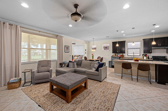 living area with recessed lighting, ornamental molding, a textured ceiling, and light tile patterned flooring